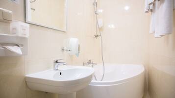 A bathroom with a sink, a mirror, a toilet paper holder, and a shower.