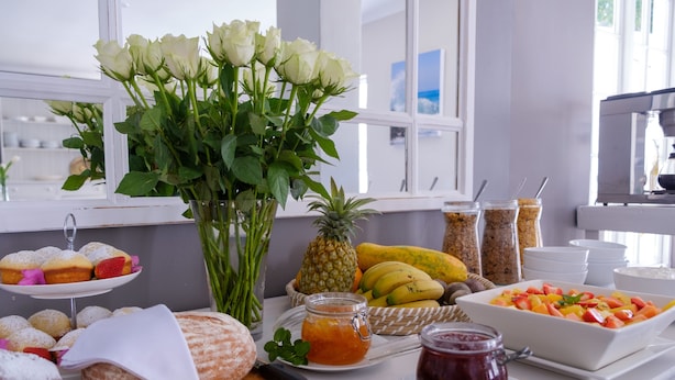 Ein Frühstücksbuffet mit Backwaren, Früchten und Blumen.