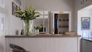Eine Küchenarbeitsplatte mit einem Blumenstrauß, einem Barhocker und einer Tafel mit einer Willkommensbotschaft.
