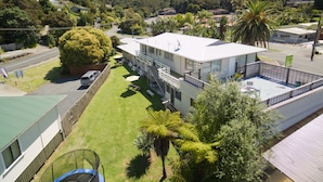 A hotel with a flat roof, multiple windows, and a fenced outdoor area with chairs and tables. - Aarangi Tui Motel (Paihia)