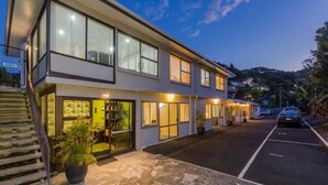 A modern two-story building with large windows, a covered outdoor area, and a parking lot. - Aarangi Tui Motel (Paihia)