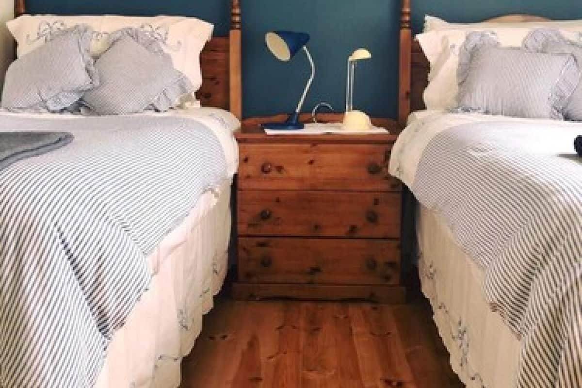 Un dormitorio con dos camas, mesitas de noche de madera y un aparador.