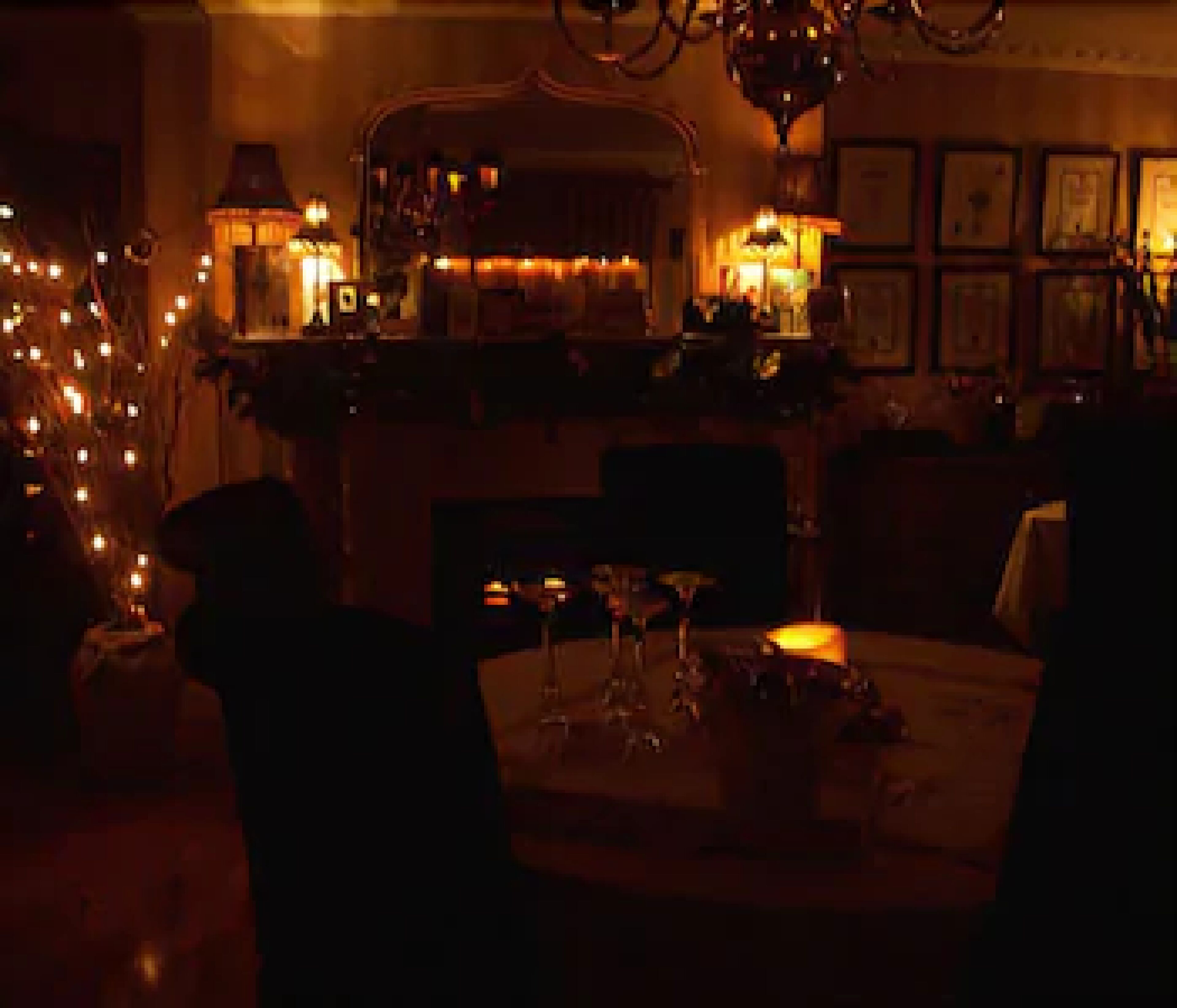 A dimly lit room with a table set for dining, chairs, and a chandelier.