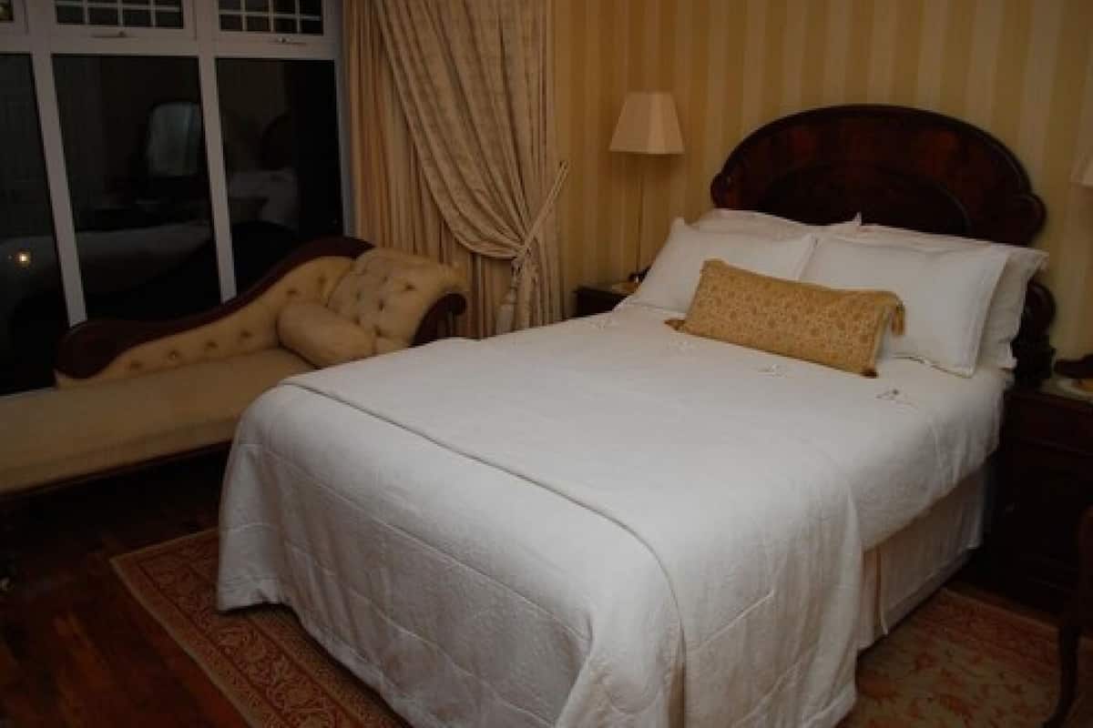 Una cama bien hecha con ropa blanca y una única almohada decorativa.