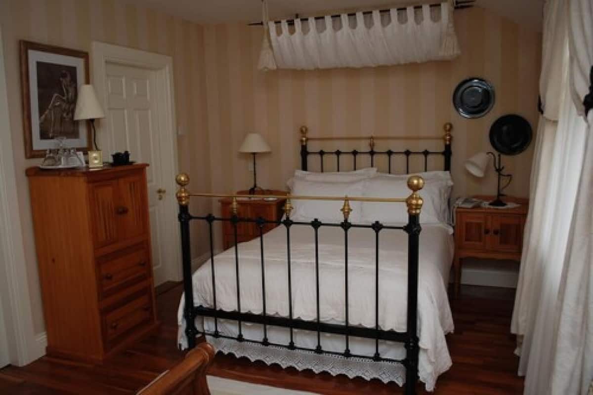 Un dormitorio con cama con dosel, cómoda de madera y mesita de noche con lámpara.