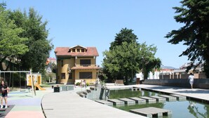 Un parque público con piscina, parque infantil y un edificio de tejado rojo.