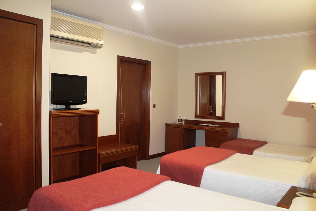 Une chambre d’hôtel avec deux lits, une télévision, un bureau, un miroir et un appareil de climatisation.