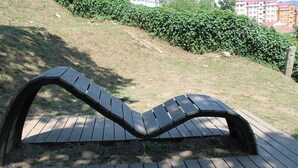 Un banco de madera con respaldo curvo sobre una cubierta de madera.