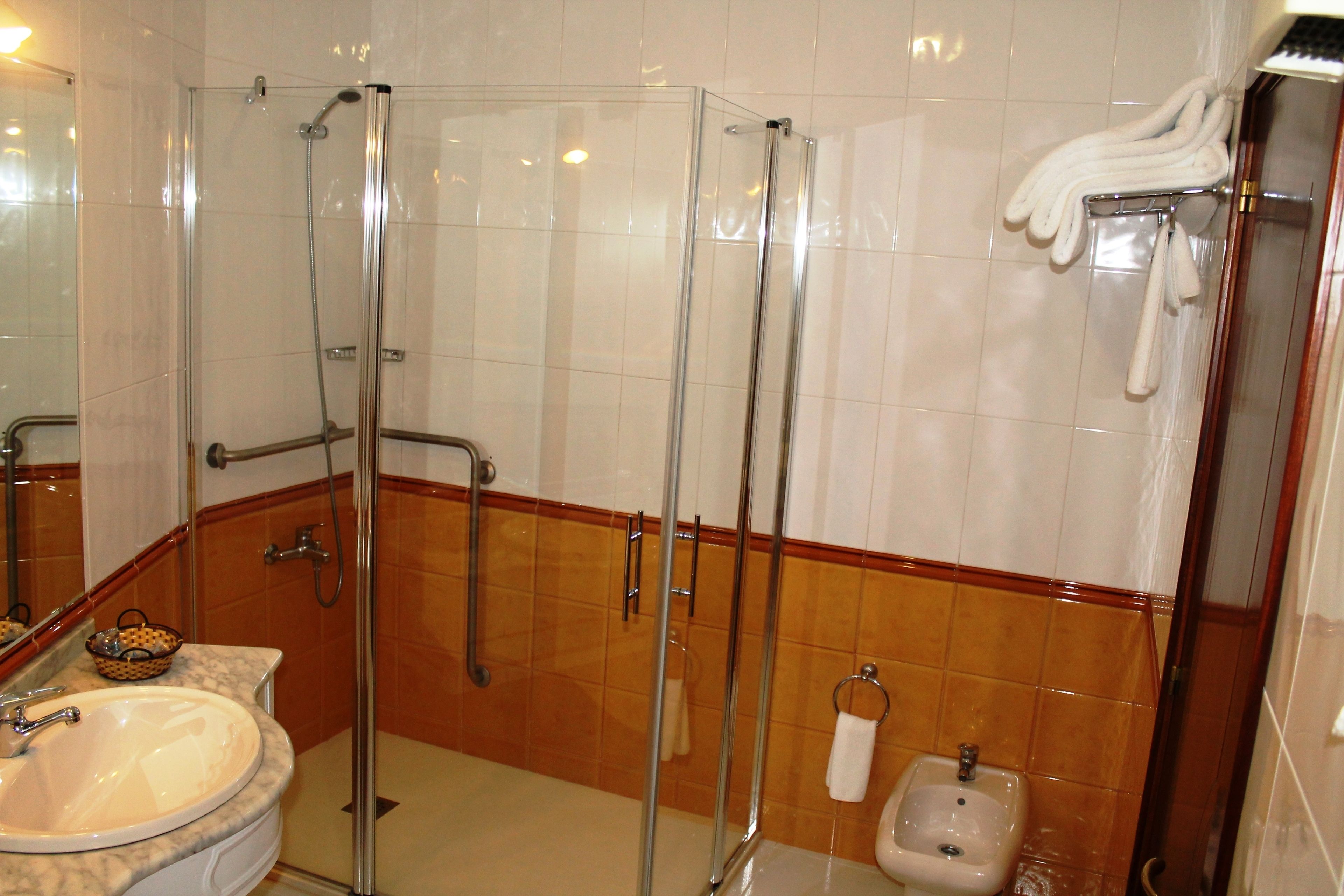 A bathroom with a glass-enclosed shower, a sink, and a toilet.