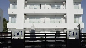 Een wit, meerlaags woongebouw met balkons, huisnummer 50, en een hekwerk.