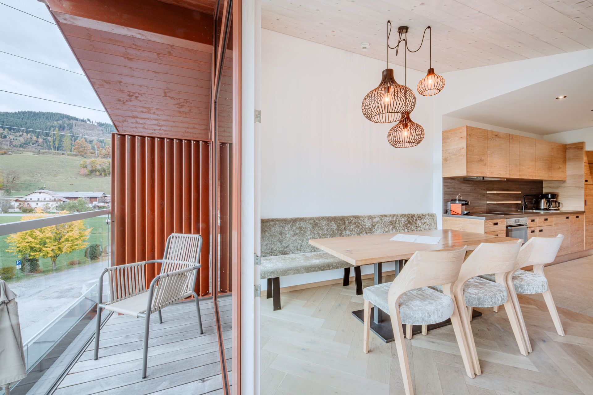 A modern kitchen with wooden cabinets and a dining area with a bench and chairs.