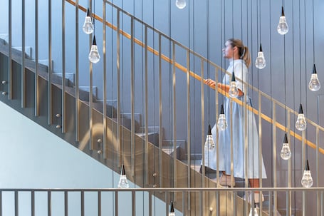 A staircase with a metal railing and hanging light fixtures.