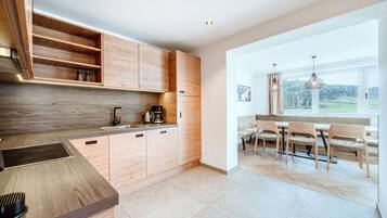 Una cocina moderna con armarios de madera, una isla integrada y un comedor con vistas al exterior.