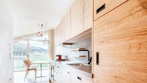 Une cuisine moderne avec des meubles en bois, un évier en acier inoxydable et une vue sur l’extérieur.