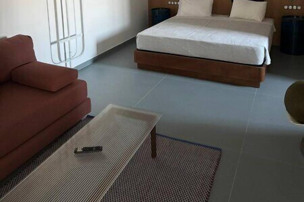 A modern bedroom with a bed, bedside tables, a hanging light fixture, and a sofa.