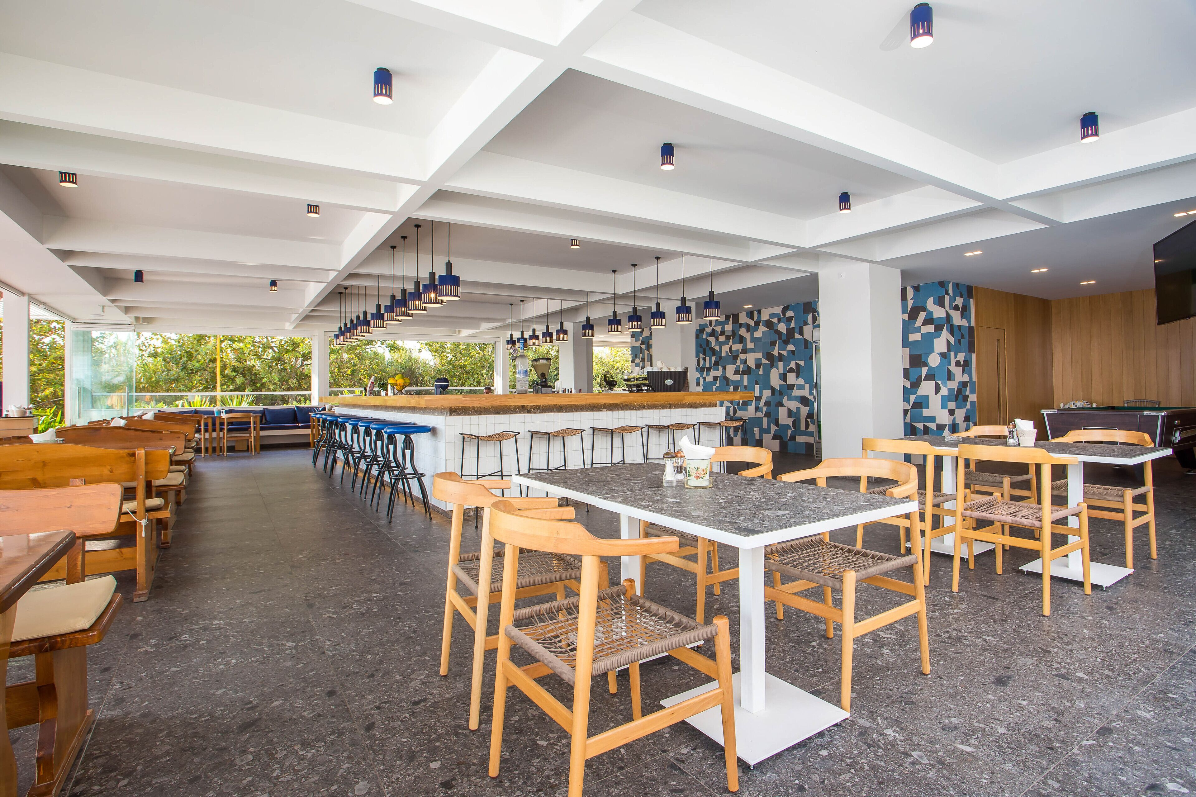 Un restaurante moderno con techos altos, sillas de madera y una zona de bar.