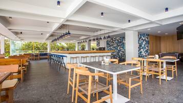 Un restaurante moderno con techos altos, sillas de madera y una zona de bar.