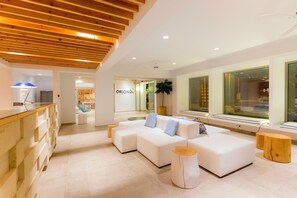 A modern hotel lobby with a wooden ceiling, a white sofa set, a reception desk, and a large window offering a view. - Orion Hotel Faliraki (Rhodes)