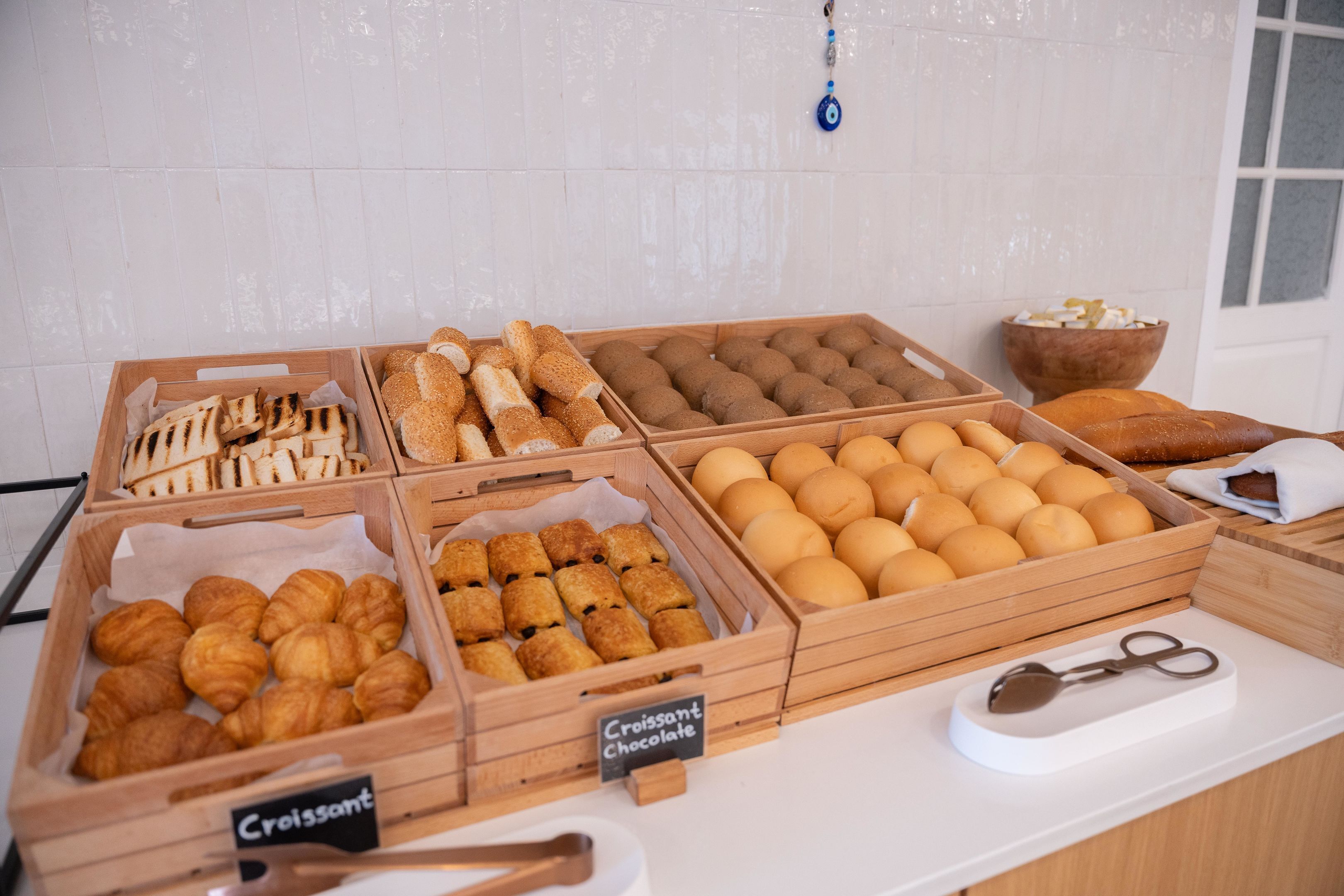A bakery display with various baked goods including croissants, bread, and rolls.