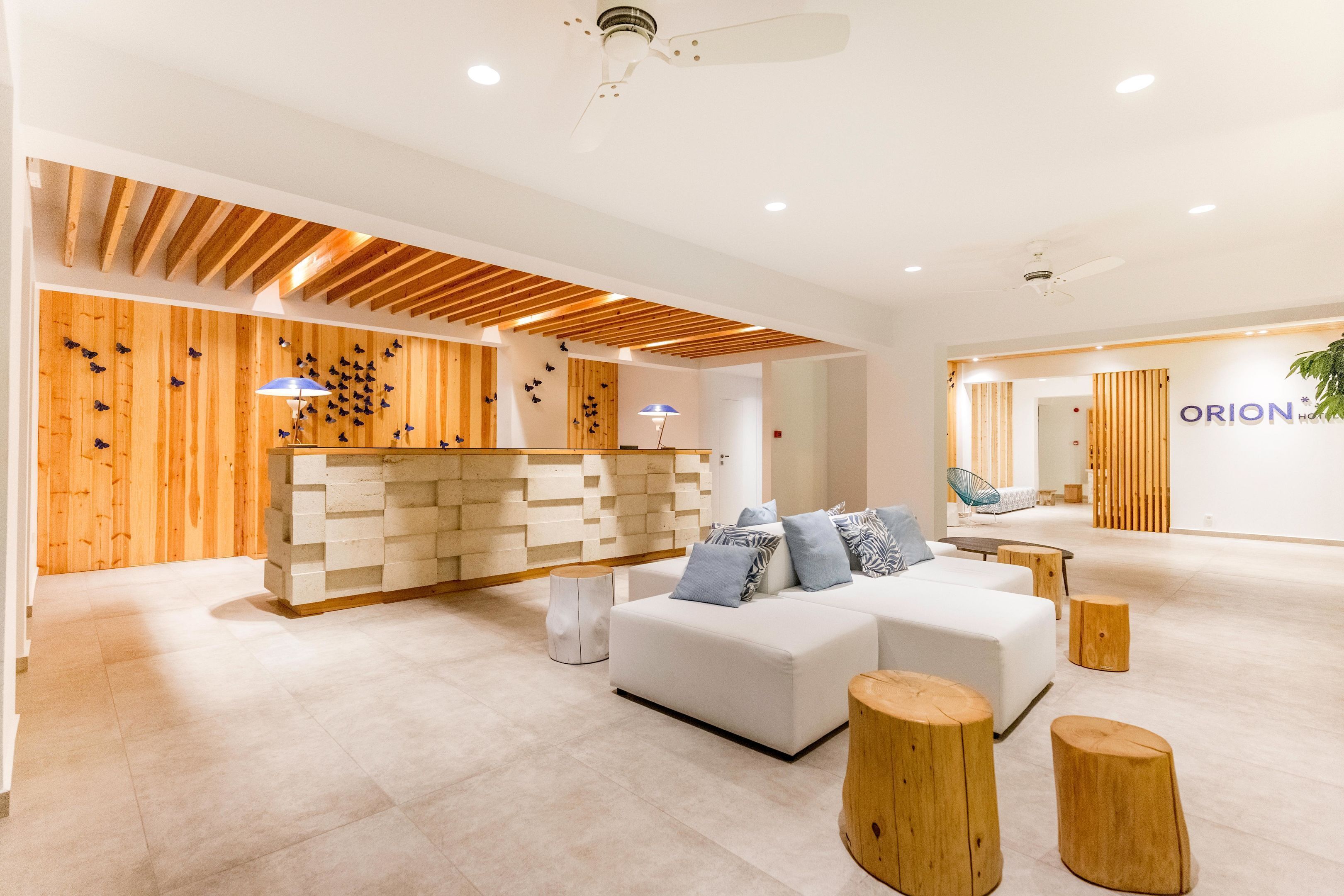 Un área de recepción moderna con un sofá blanco, detalles de madera y un mostrador de recepción.