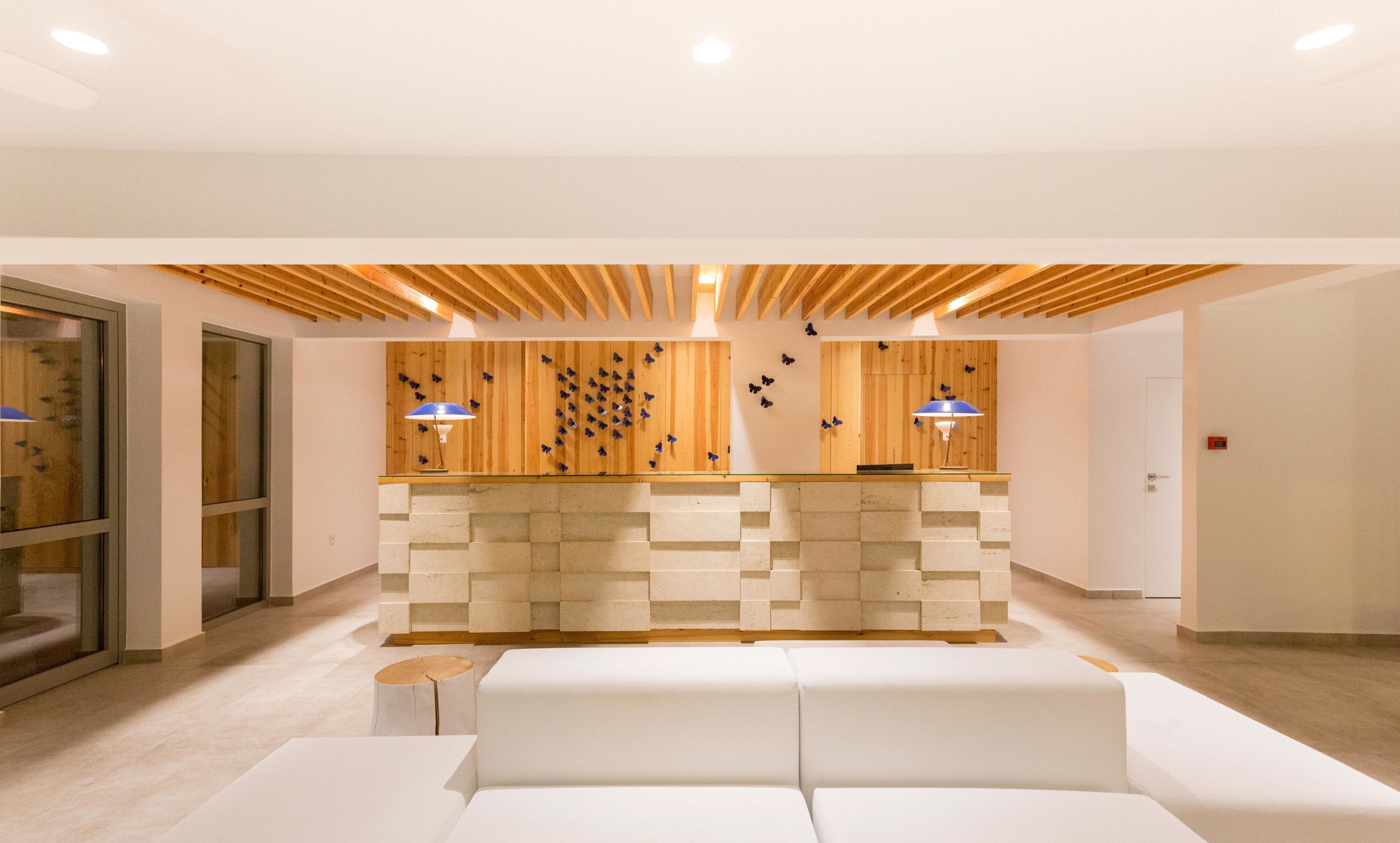 Una moderna área de recepción con una pared de madera, un mostrador de recepción blanco y un sofá blanco.