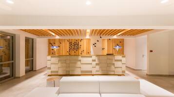 Una moderna área de recepción con una pared de madera, un mostrador de recepción blanco y un sofá blanco.
