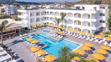 Un hotel con un amplio espacio de piscina, varios niveles de balcones y vistas del paisaje circundante.