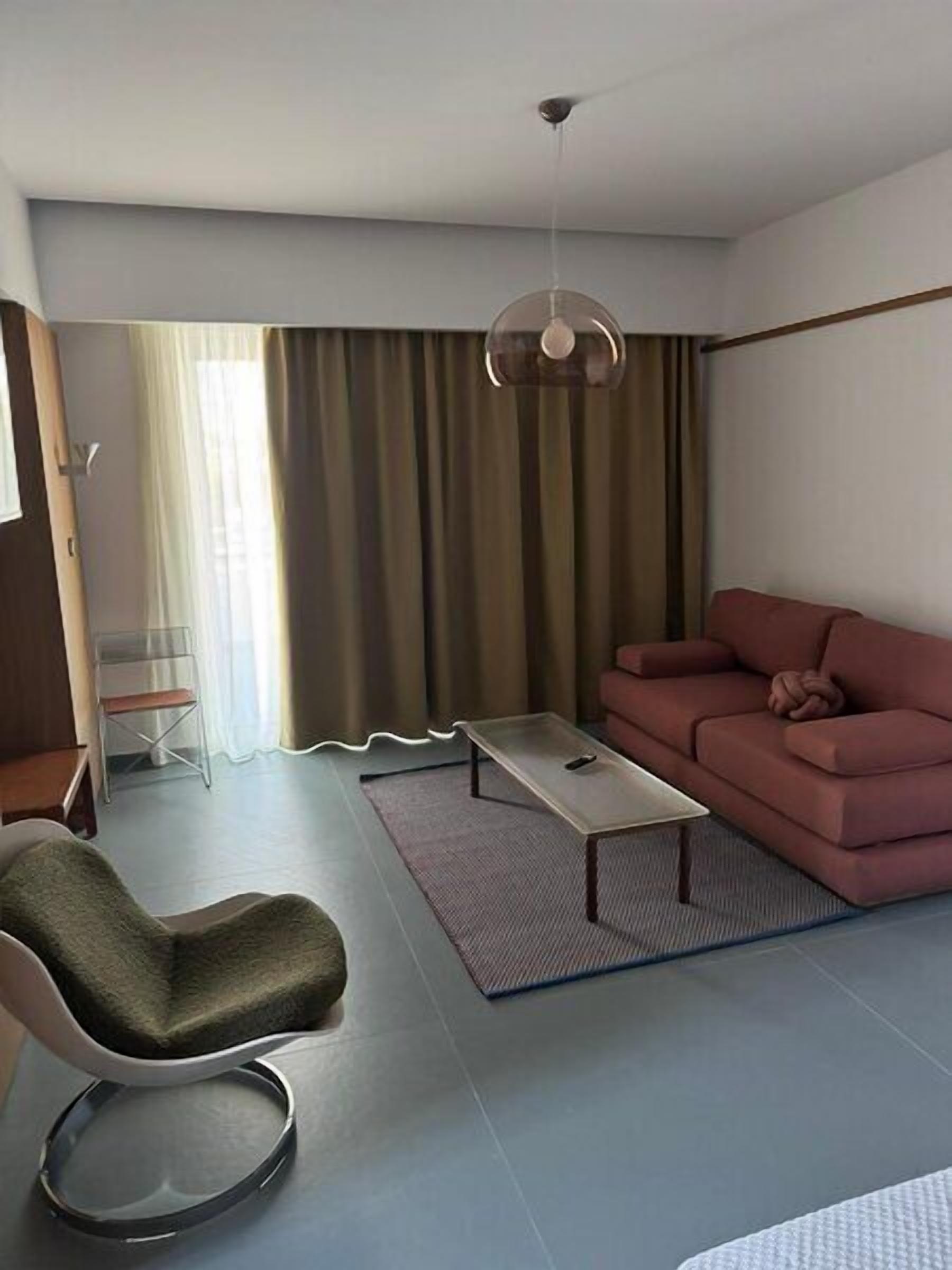 A modern living room with a sofa, a chair, a coffee table, and a hanging light fixture.