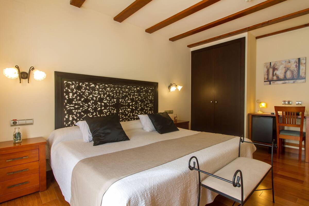 Ein Schlafzimmer mit einem Bett, Nachttischen, einem Schreibtisch und einem Sessel.