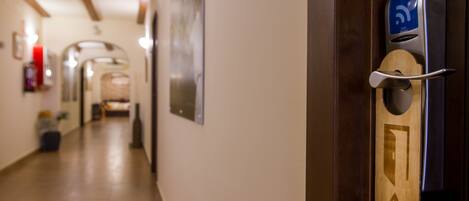 A hallway with a wooden door featuring a keycard reader and a directional arrow sign.
