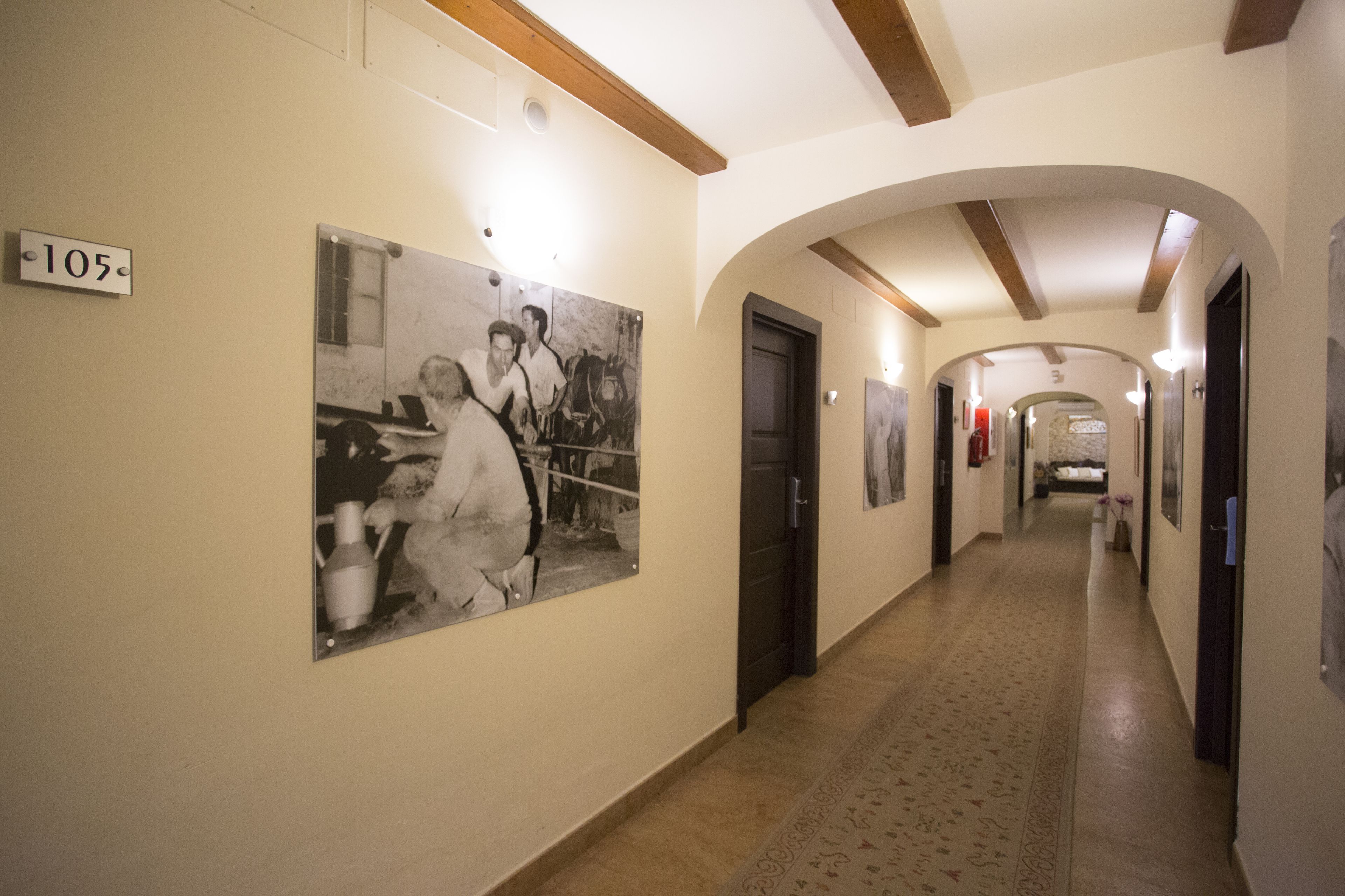 Un couloir avec un panneau indiquant le numéro « 105 » sur le mur, une grande photographie en noir et blanc et un tapis à motifs.