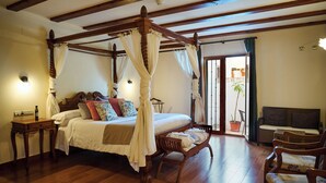 A four-poster canopy bed with a wooden frame, a bedside table with a lamp, and a seating area with a sofa and chairs. - Hotel Tossal d'Altea (Altea)