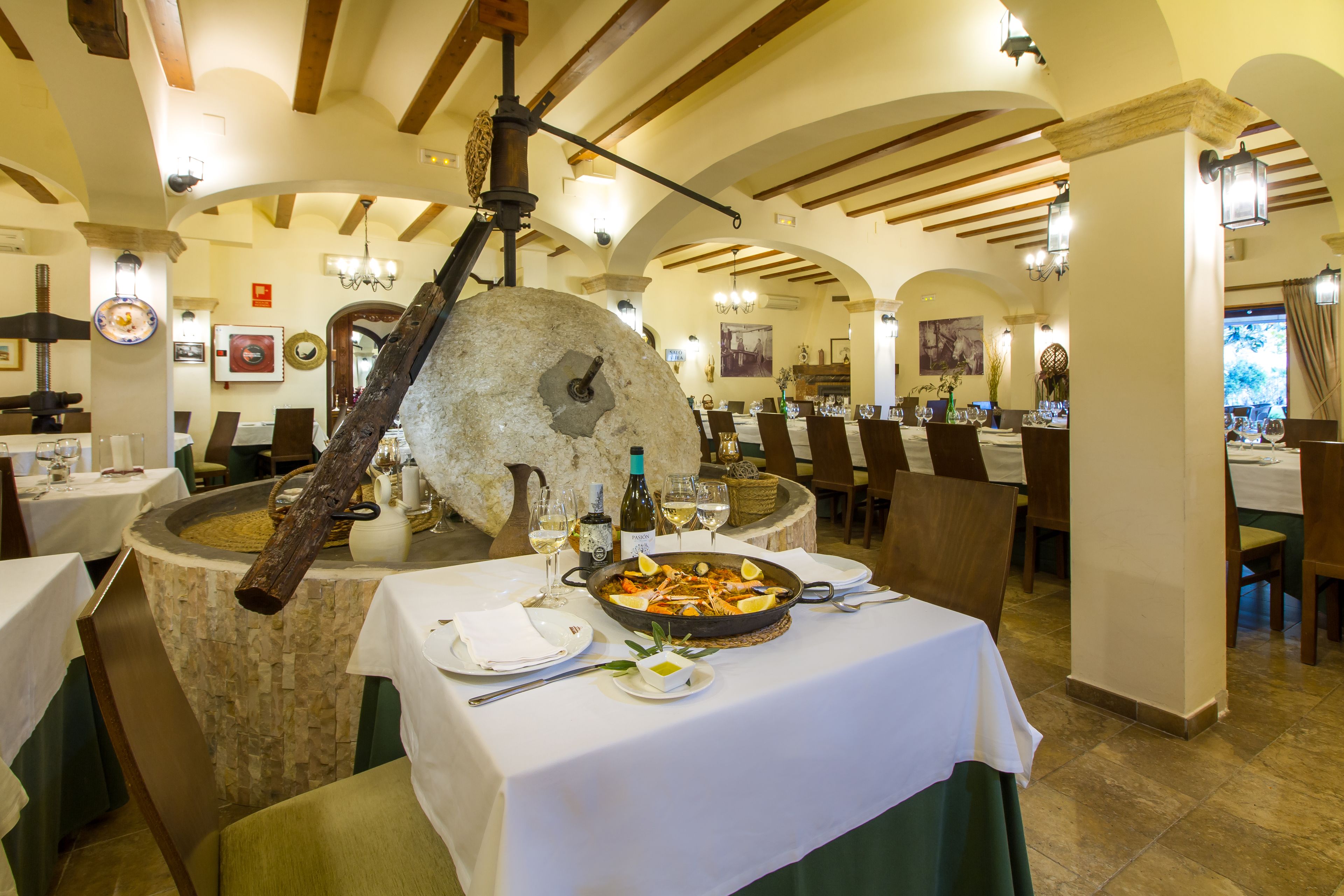 A restaurant with a stone centerpiece, white tablecloths, and wooden beams.
