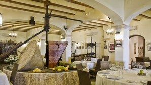 A restaurant with rustic decor, stone walls, and wooden beams. Tables are set with white tablecloths and wine glasses. - Hotel Tossal d'Altea (Altea)