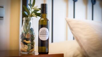 Una botella de vino del Hotel Tossal D'Alaea, una jarra de cristal con piedras decorativas y una planta sobre una mesa de madera.