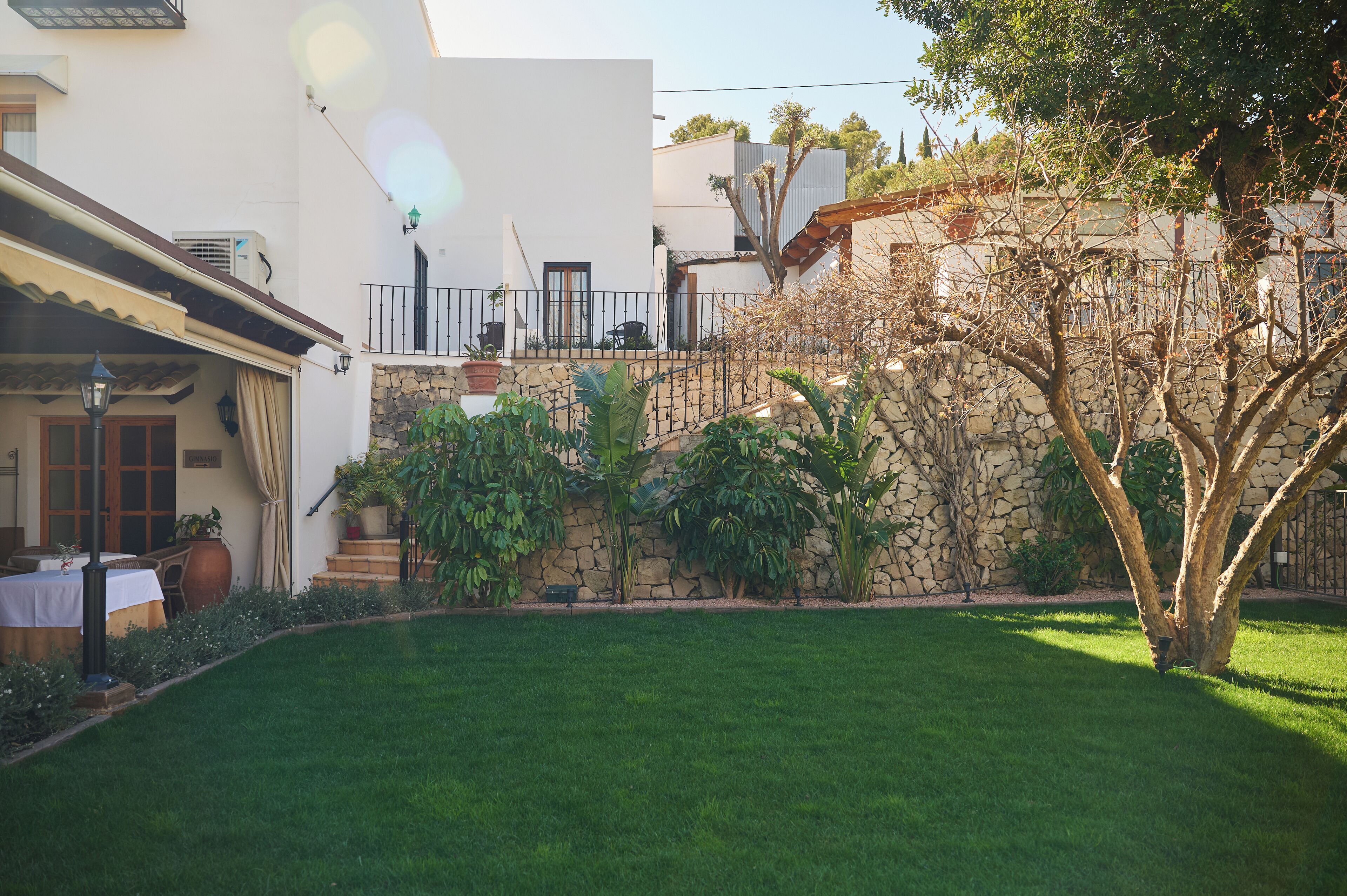 A well-maintained garden with a stone wall, a lawn, and a patio area with outdoor furniture.