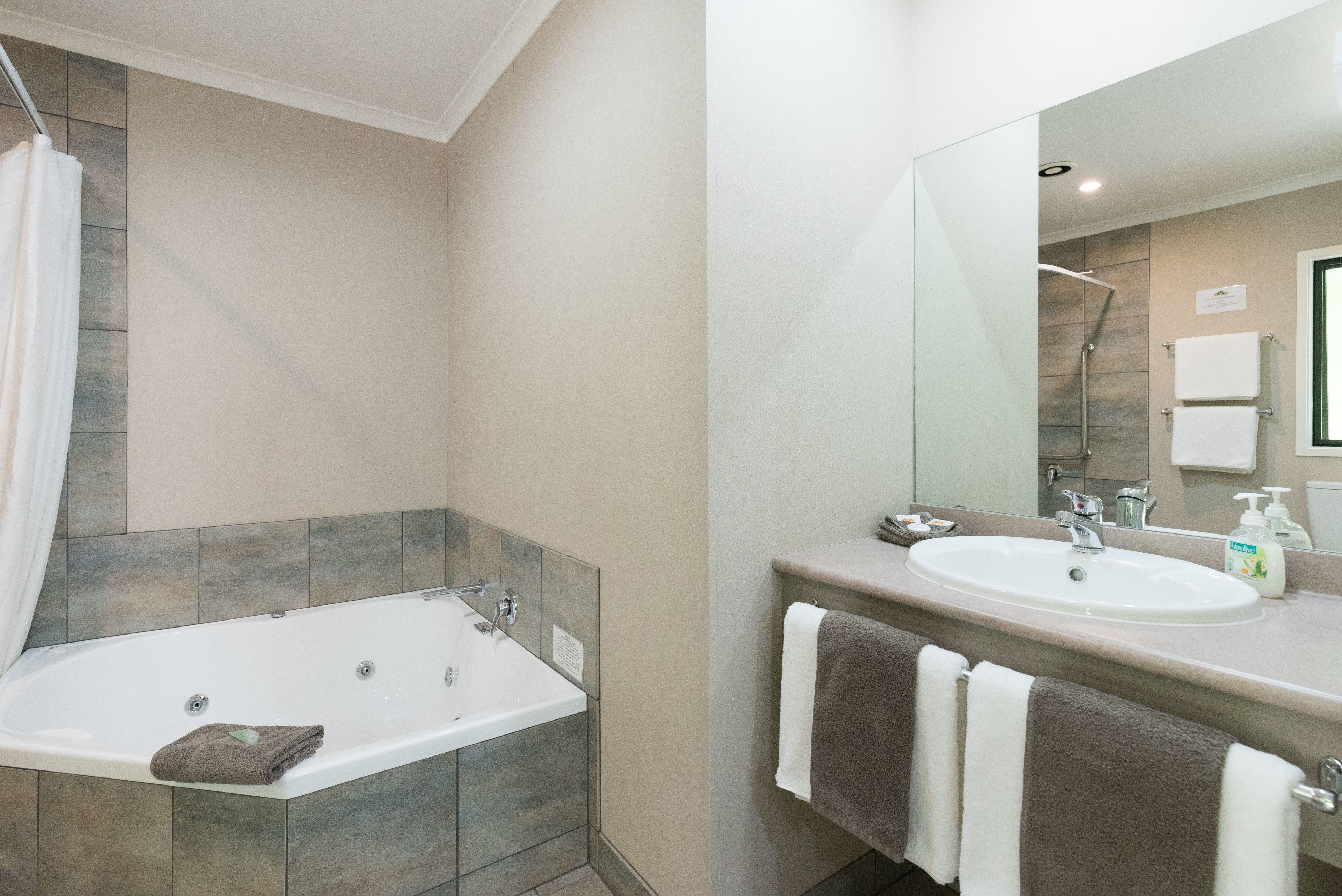 A modern bathroom with a bathtub, a sink, and a large mirror.