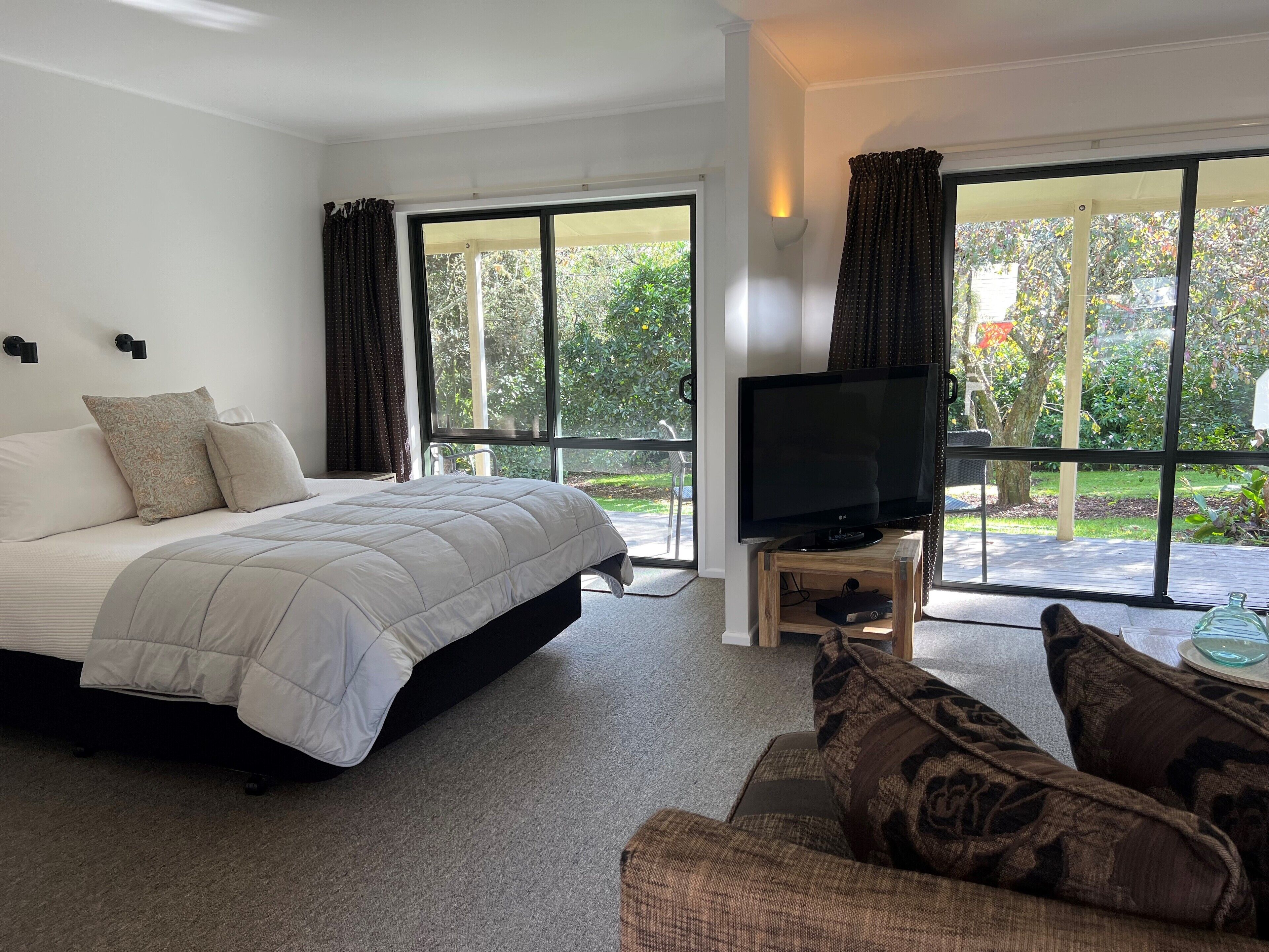 A bedroom with a bed, a TV on a wooden stand, and a sofa.