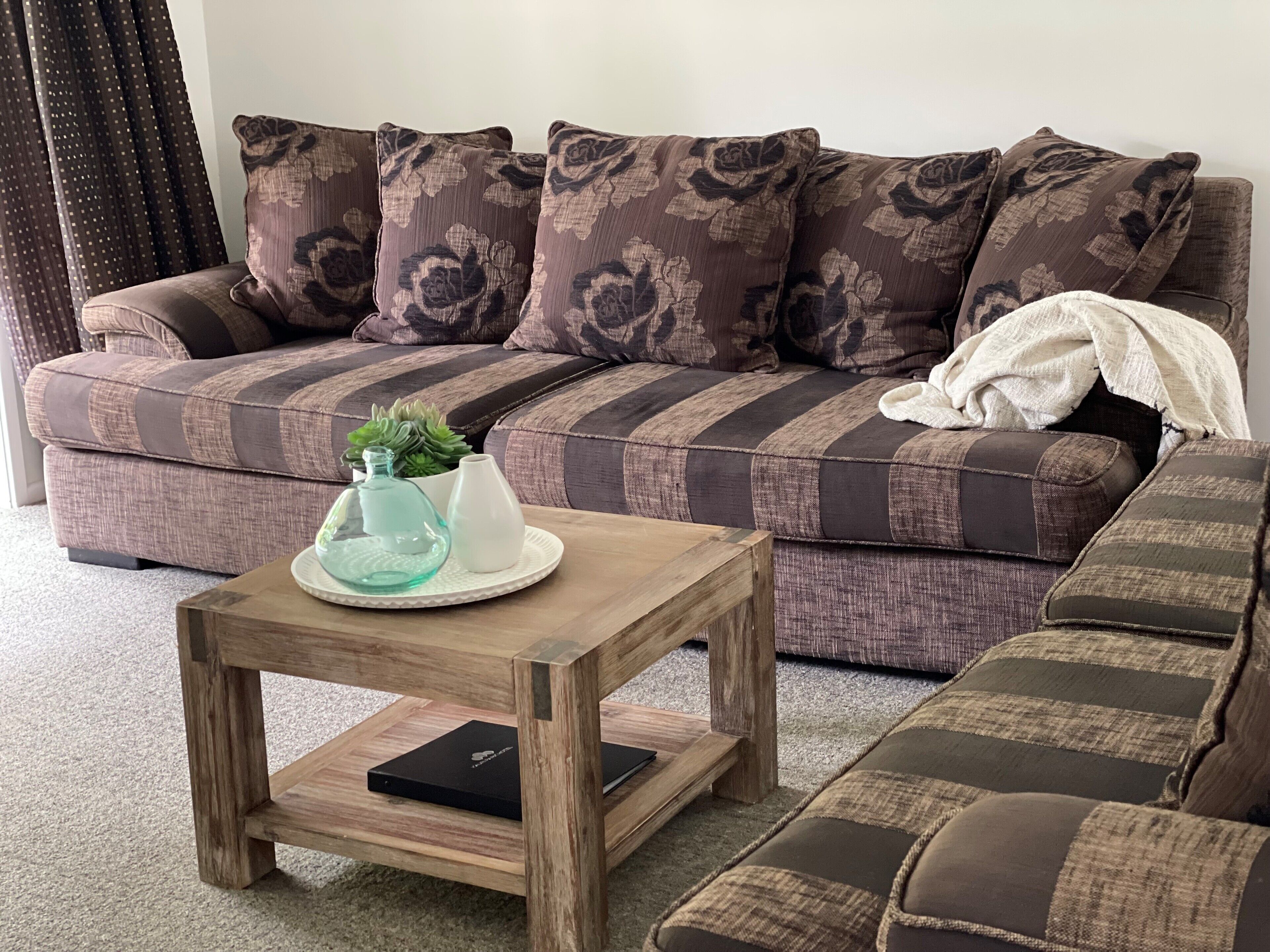 Ein Wohnzimmer mit einer Couch, einem Holztisch und einer kleinen Pflanze auf dem Tisch.