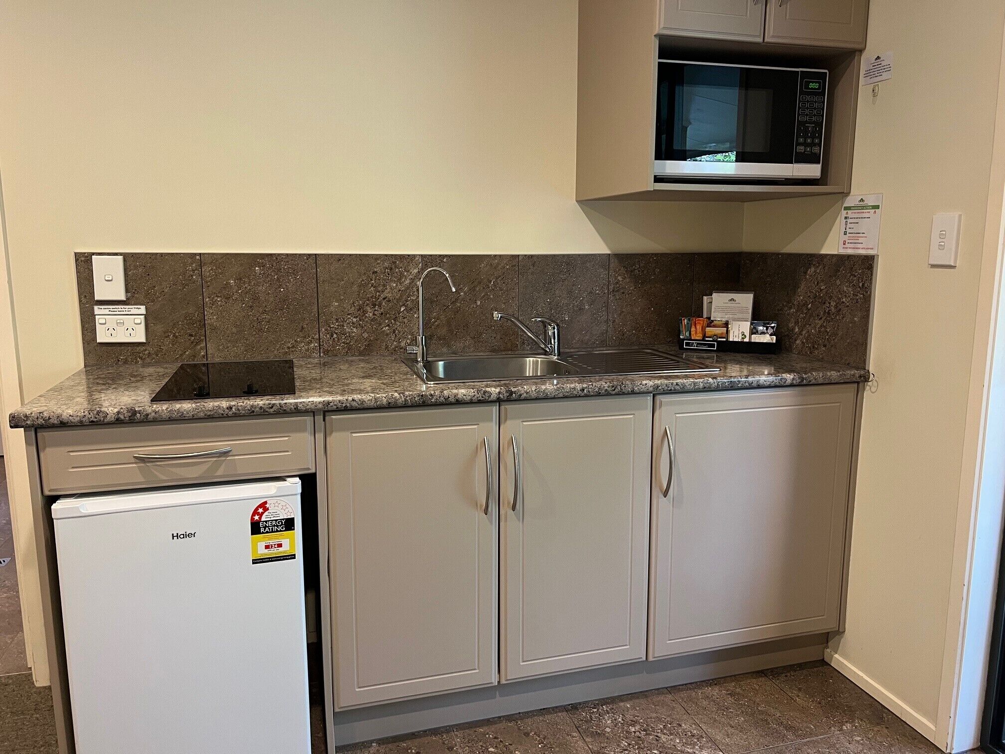 A compact kitchen with a built-in microwave, a stainless steel sink, and a dishwasher.