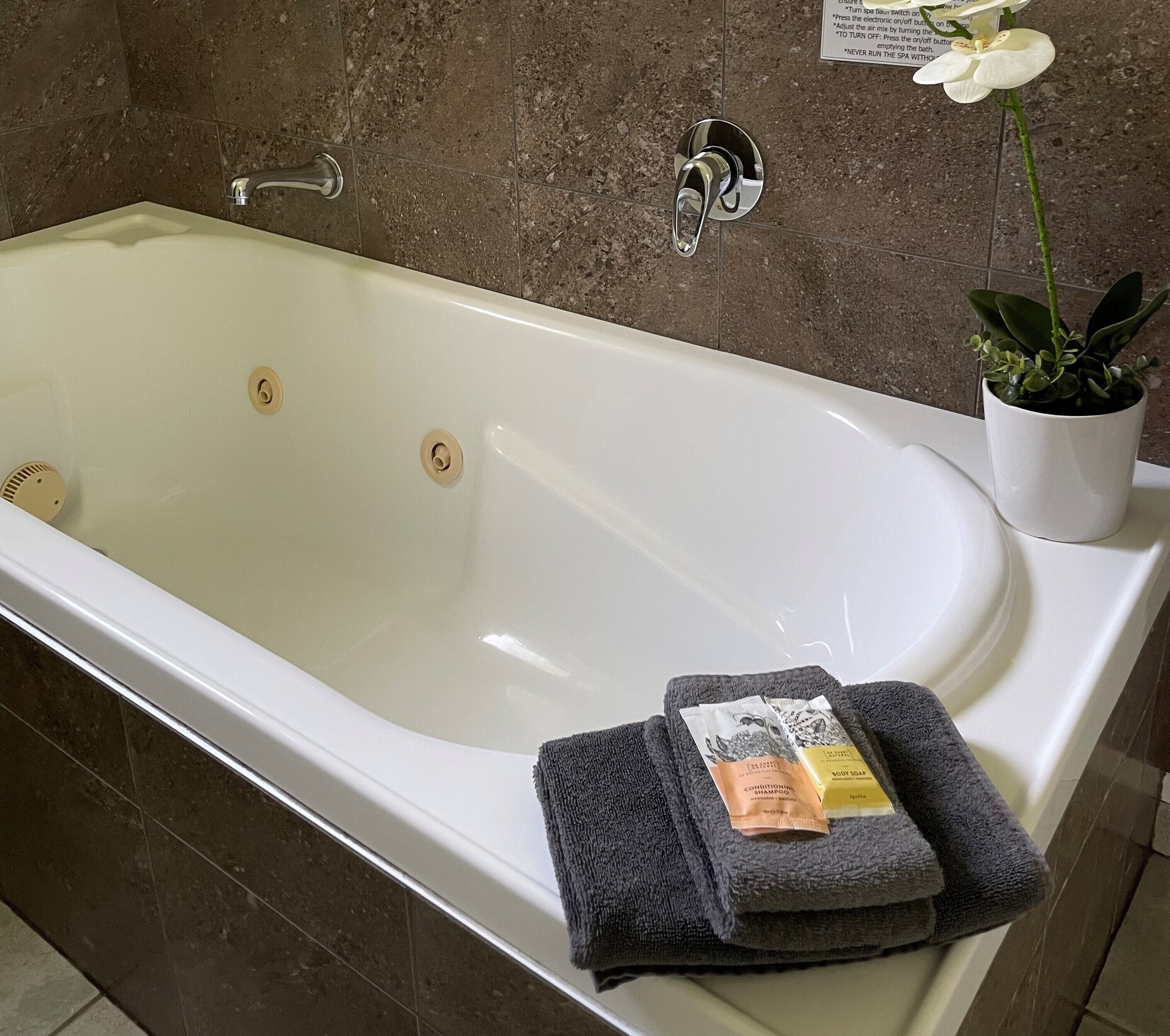 Eine Badewanne mit Wasserhahn, ein Blumentopf und ein Stapel Handtücher.
