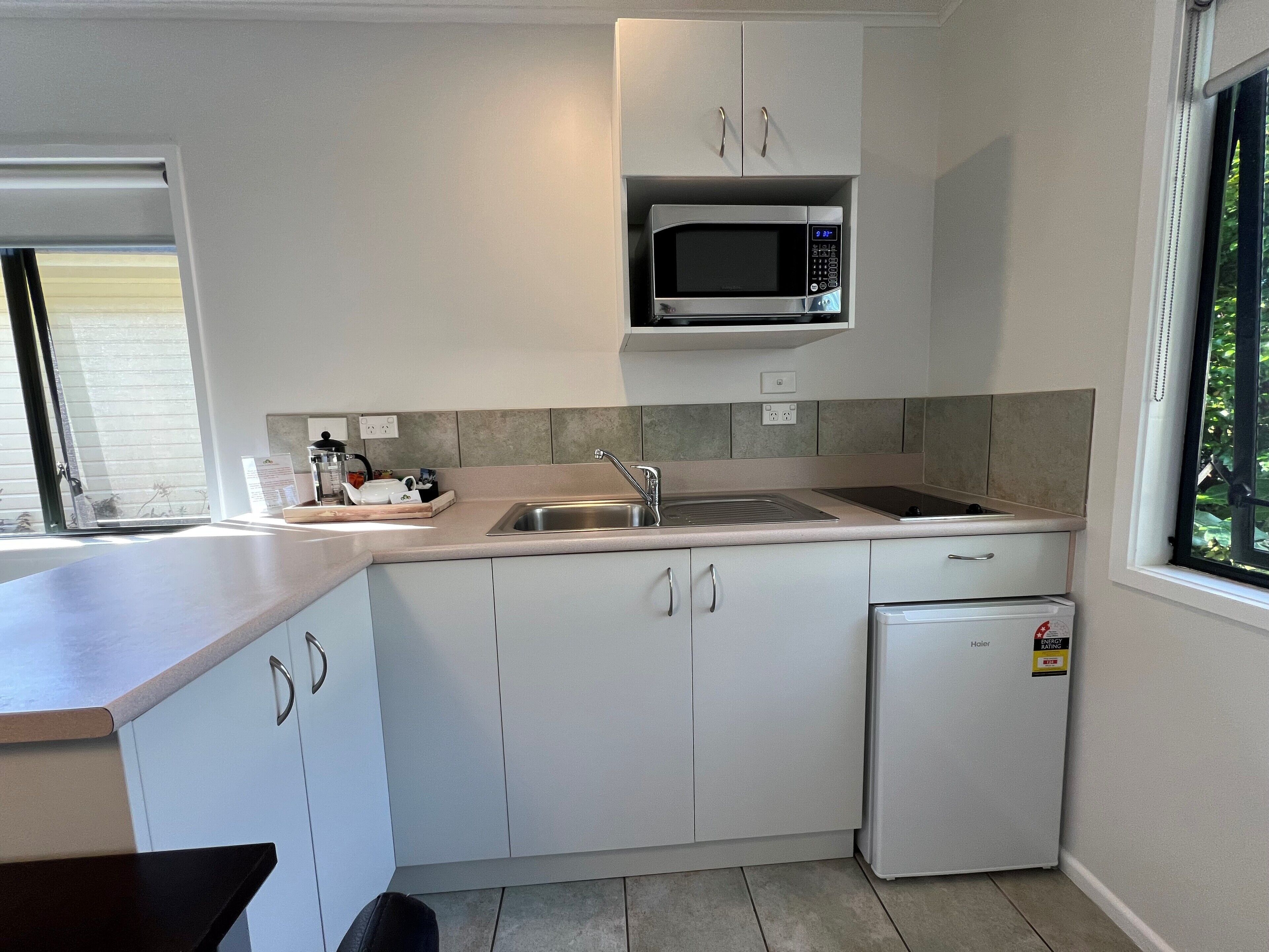 A compact kitchen with a microwave, sink, and a small refrigerator.