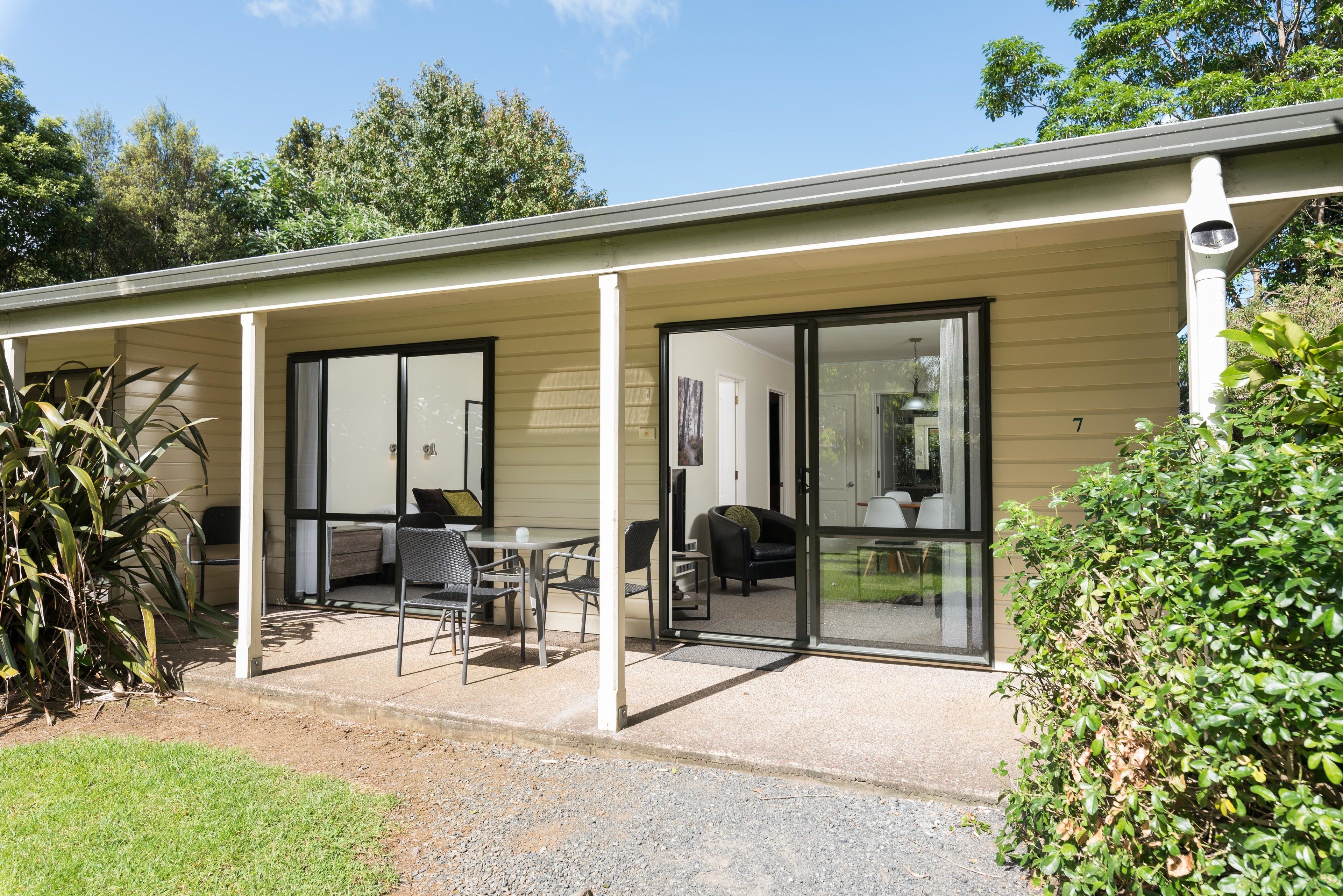A covered outdoor area with a table and chairs, a sliding glass door, and a number '7' on the wall.