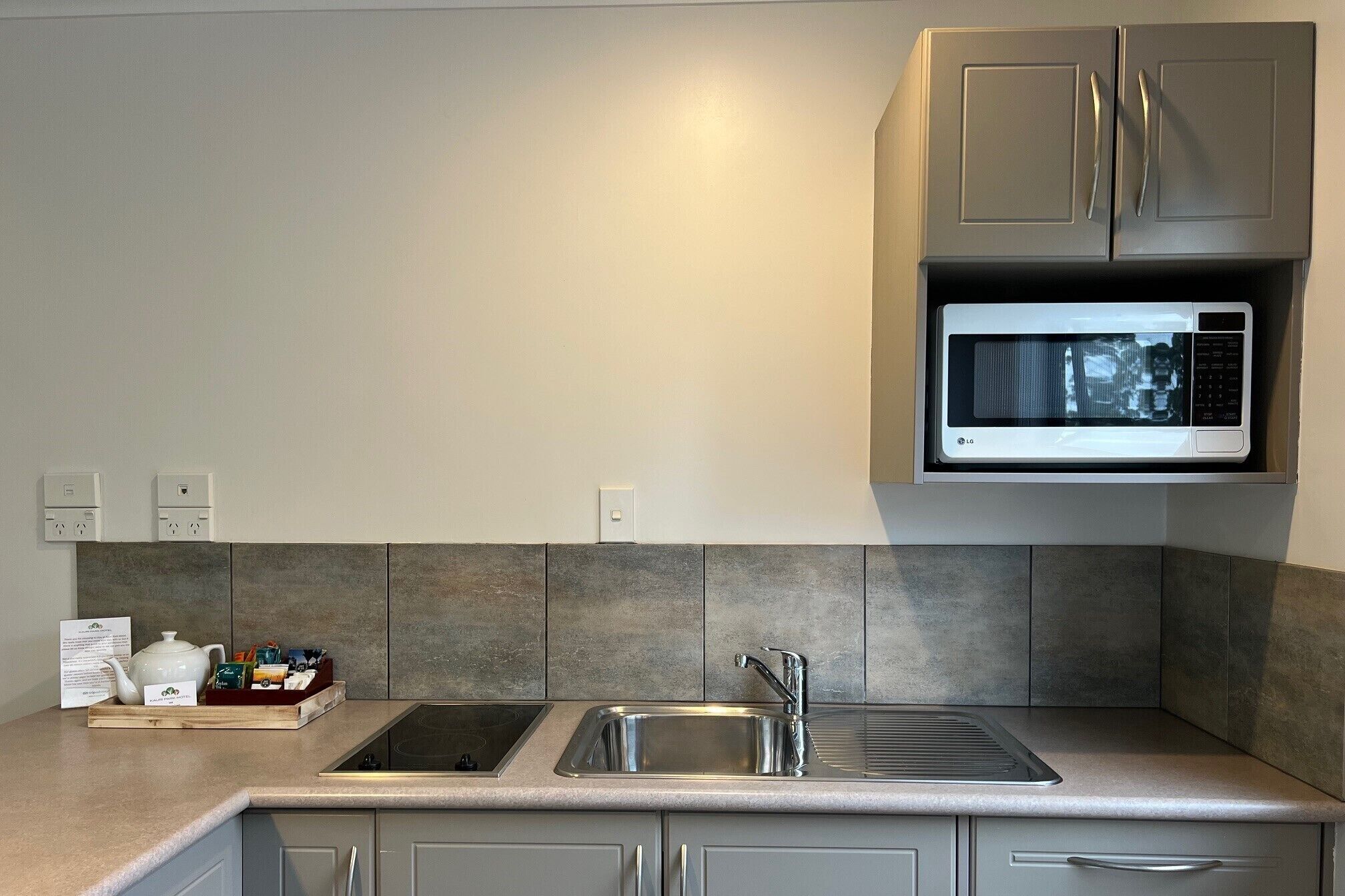 A modern kitchen with a built-in microwave, a sink, and a stovetop.