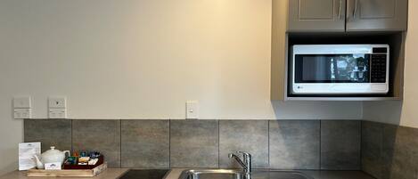 A modern kitchen with a built-in microwave, a sink, and a stovetop.