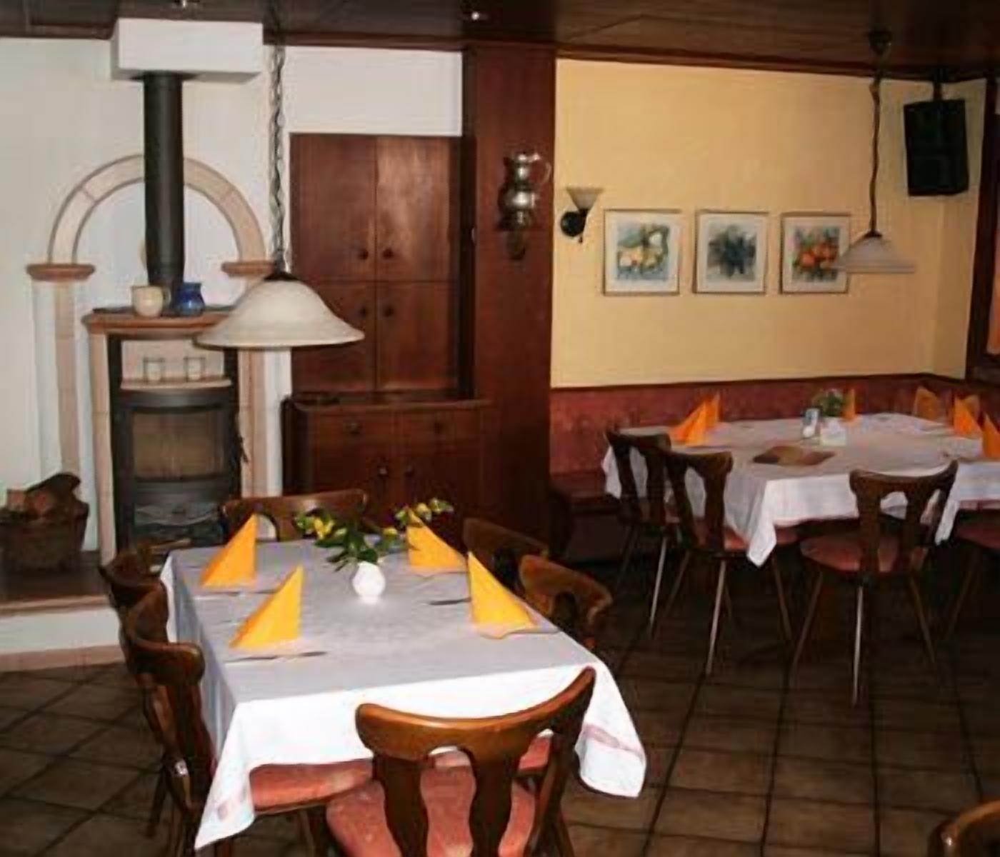 Un restaurante con mesas y sillas de madera, una chimenea y obras de arte enmarcadas en la pared.