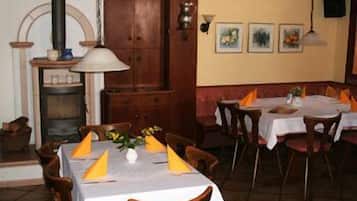 Un restaurant avec des tables et des chaises en bois, une cheminée et des œuvres d’art encadrées accrochées au mur.