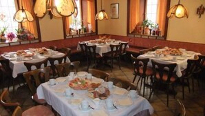A restaurant with multiple round tables covered with white tablecloths, each set with plates, cups, and cutlery. - Gasthof Rotes Roß (Zell im Fichtelgebirge)