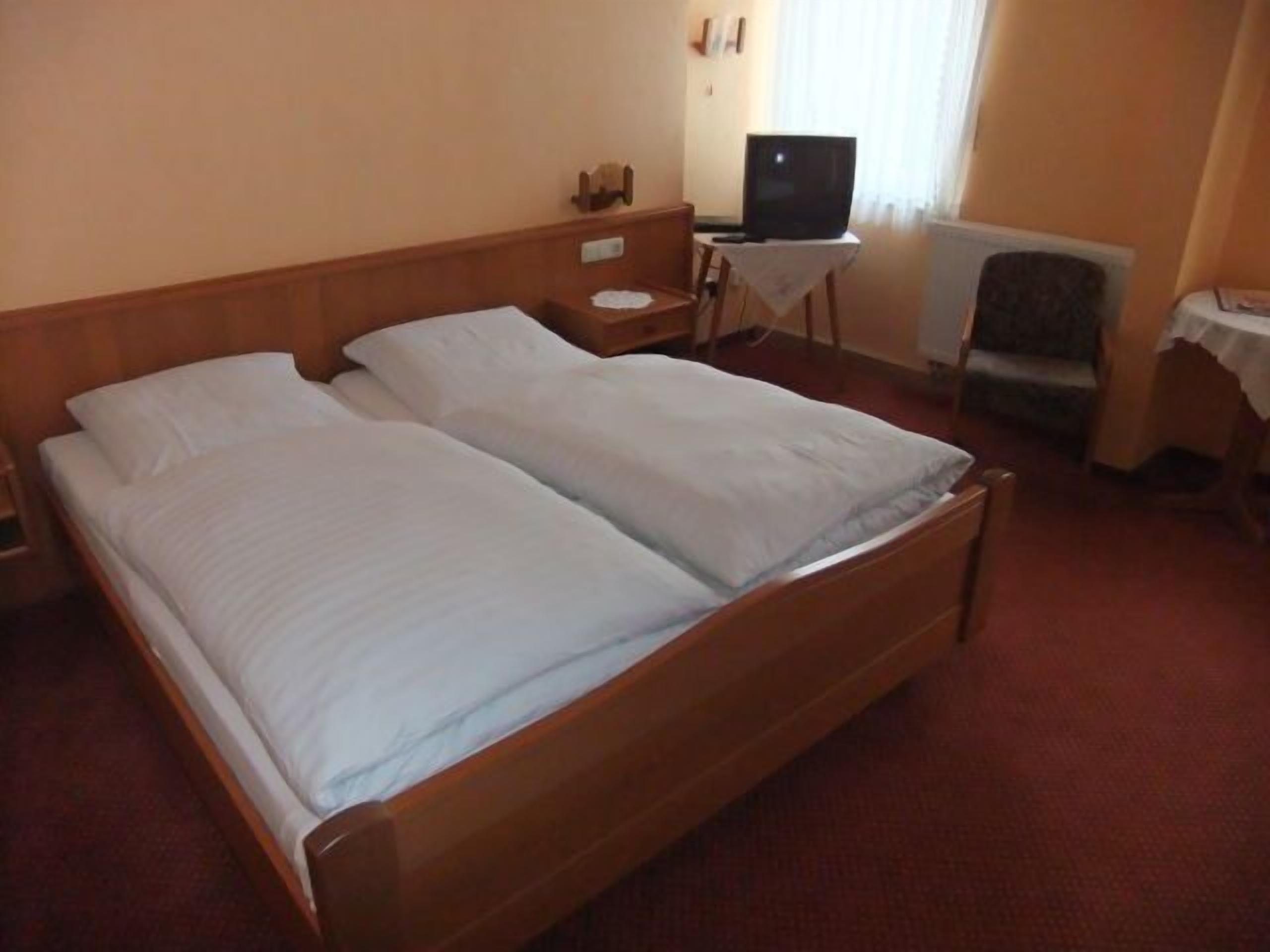 A double bed with white linens in a hotel room.