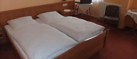 A double bed with white linens in a hotel room.